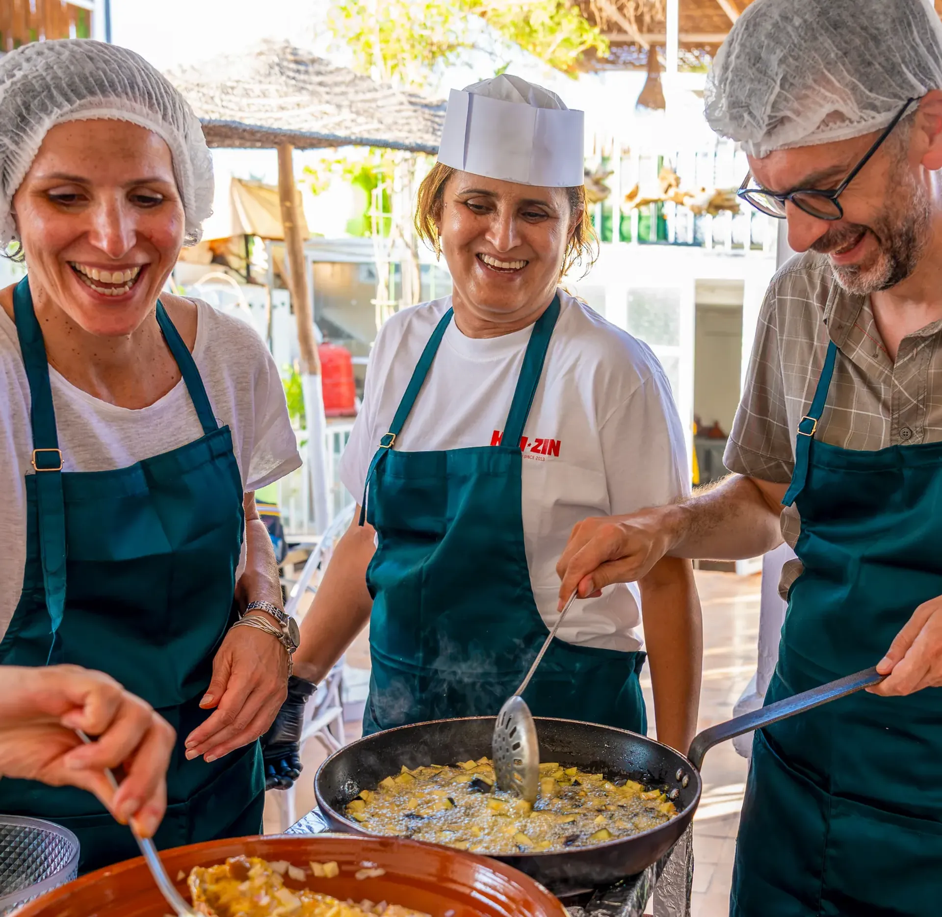 Trois participants du cours de cuisine autour d'un tajine, sur la terrasse