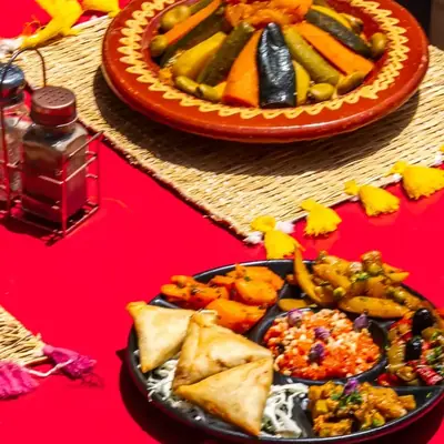 Tables rouges dressees pour le diner sur la terrasse, tajines et sets en paille