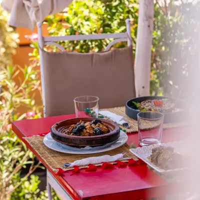 Table dressee sur la terrasse, avec un plat marocain et des verres