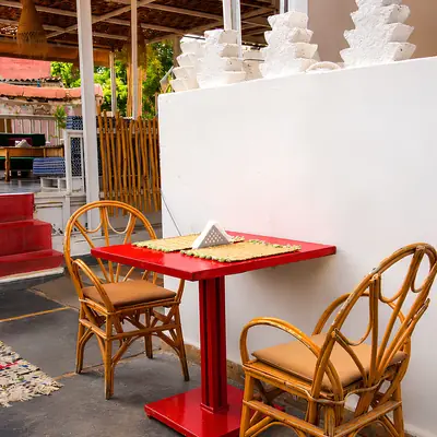 Table rouge et fauteuils en rotin sur la terrasse de Kui-Zin