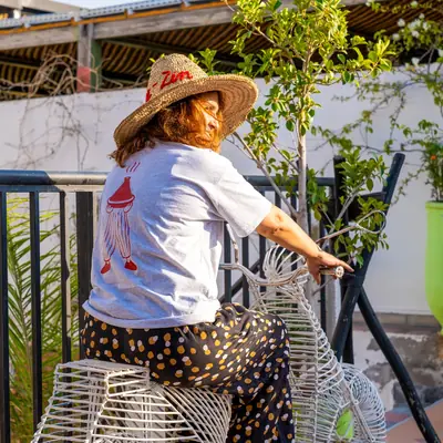 Cliente coiffee d'un chapeau de paille Kui-Zin, assise sur la terrasse