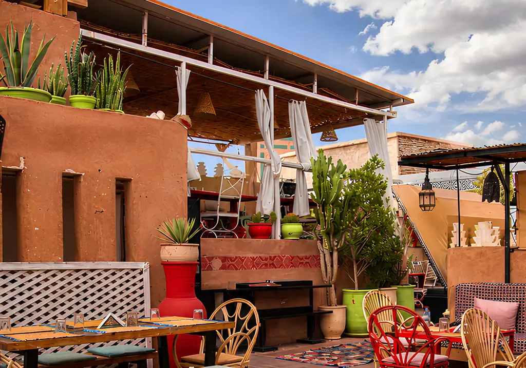 La terrasse rooftop de Kui-Zin, tapis berberes et mobilier rouge sous le ciel de Marrakech